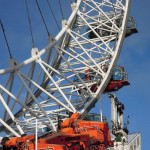 Photograph, close, daytime: detail of the London Eye orange machinery including the red "key" capsule